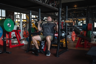 Kunde macht Schulterdrücken mit der Bandbell Langhantel.