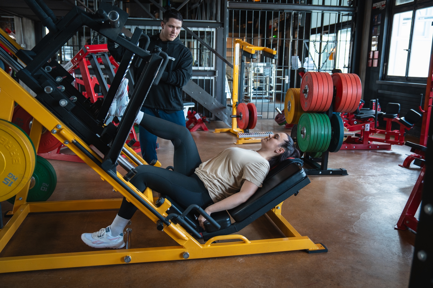 Trainer beim instruieren eines Sportlers auf der Beinpresse